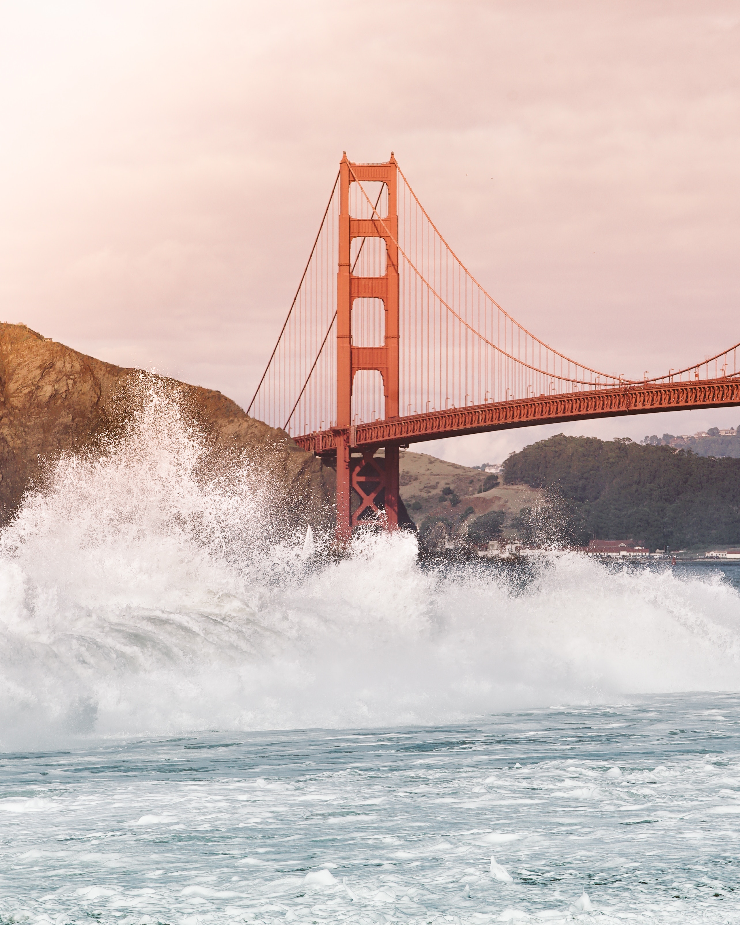 Crashing waves by a red bridge in San Francisco