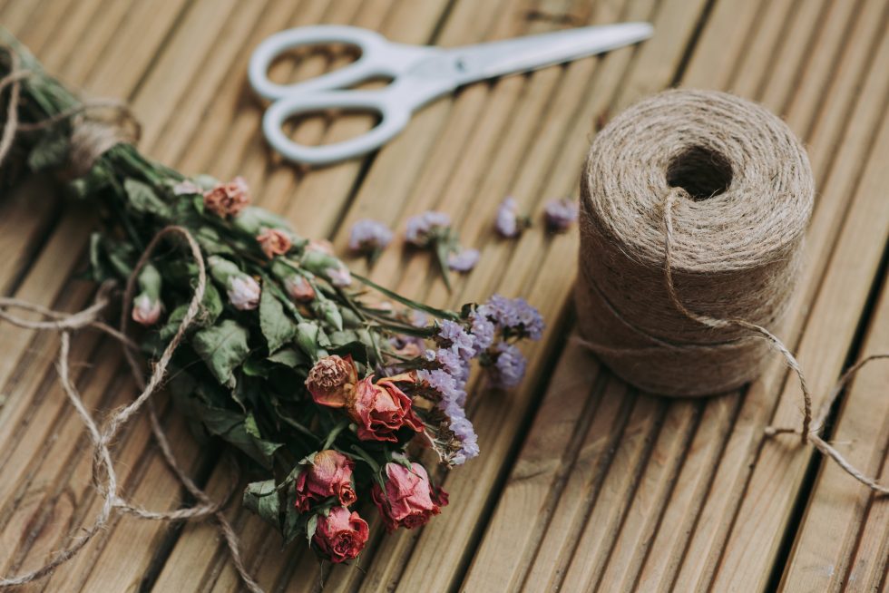 A dried flowers bouquet beside a twine coil and white scissors