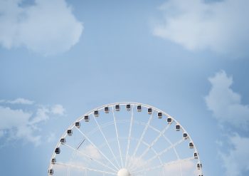 A half of a white Ferris wheel against the blue sky