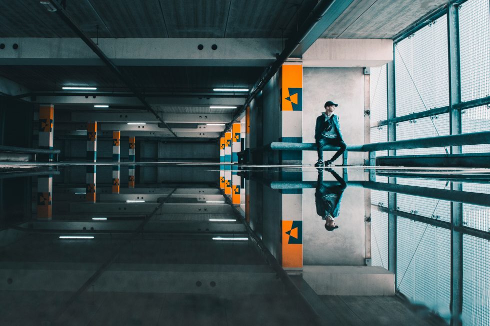 A man reflected in the water on the floor in an empty building