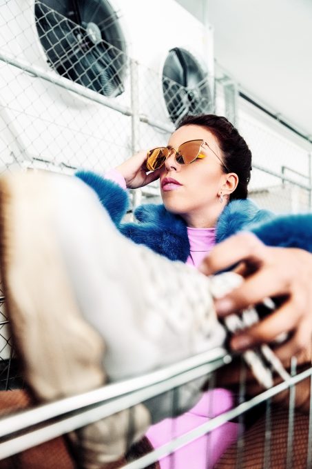 A woman sitting in a shopping cart and holding brown sunglasses