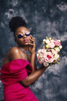 A woman wearing sunglasses and posing with a flowers bouquet