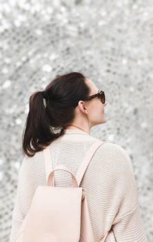 A woman wearing white sweatshirt and backpack