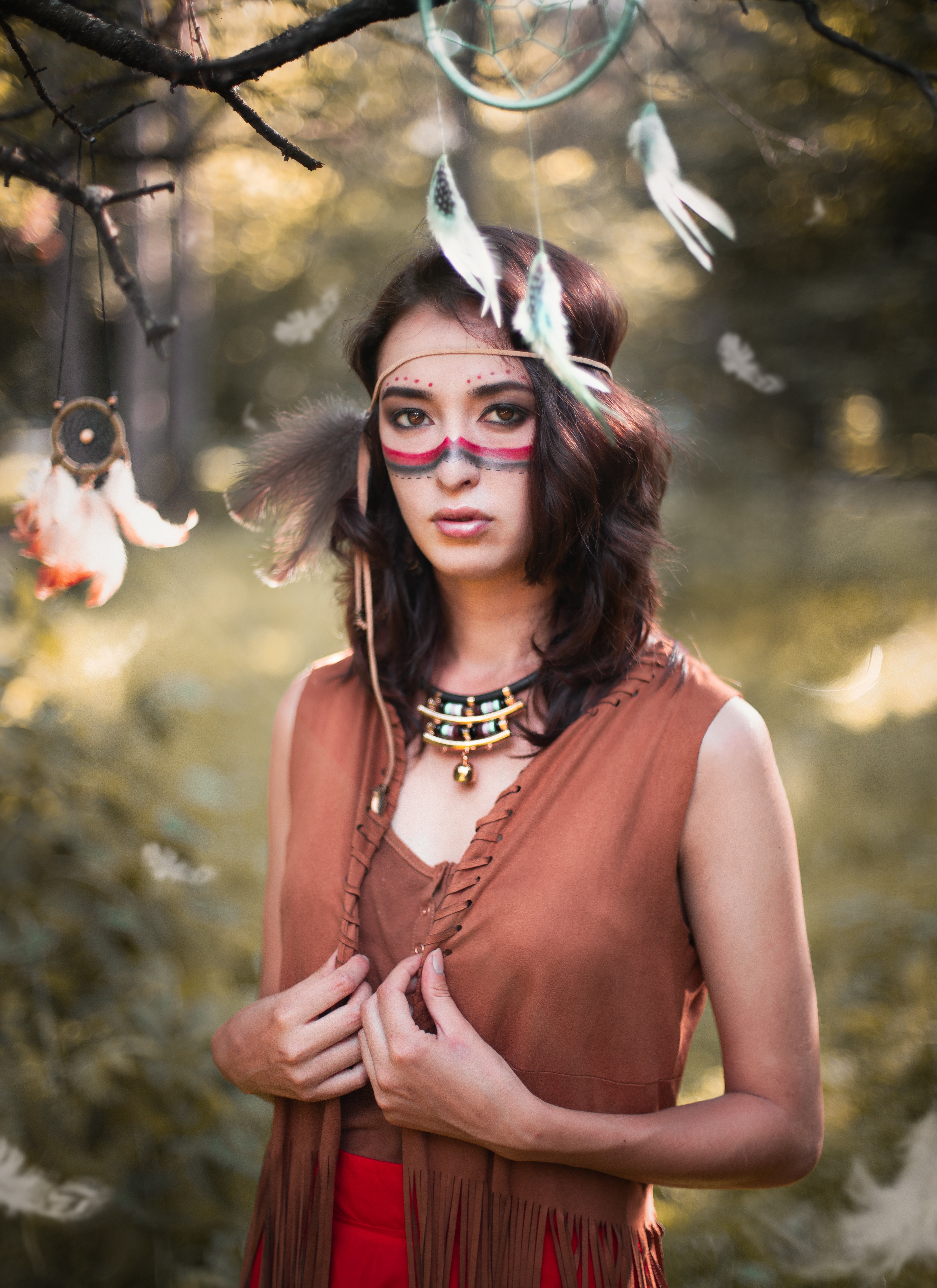 A woman with Native American face painting and dream catchers in nature