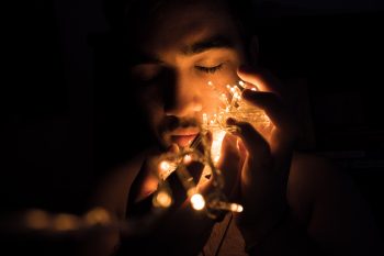 Close-up photography of a man holding Christmas lights