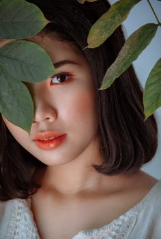 Photography of a woman hiding behind leaves