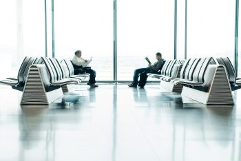 Two men sitting in front of each other in the airport waiting area