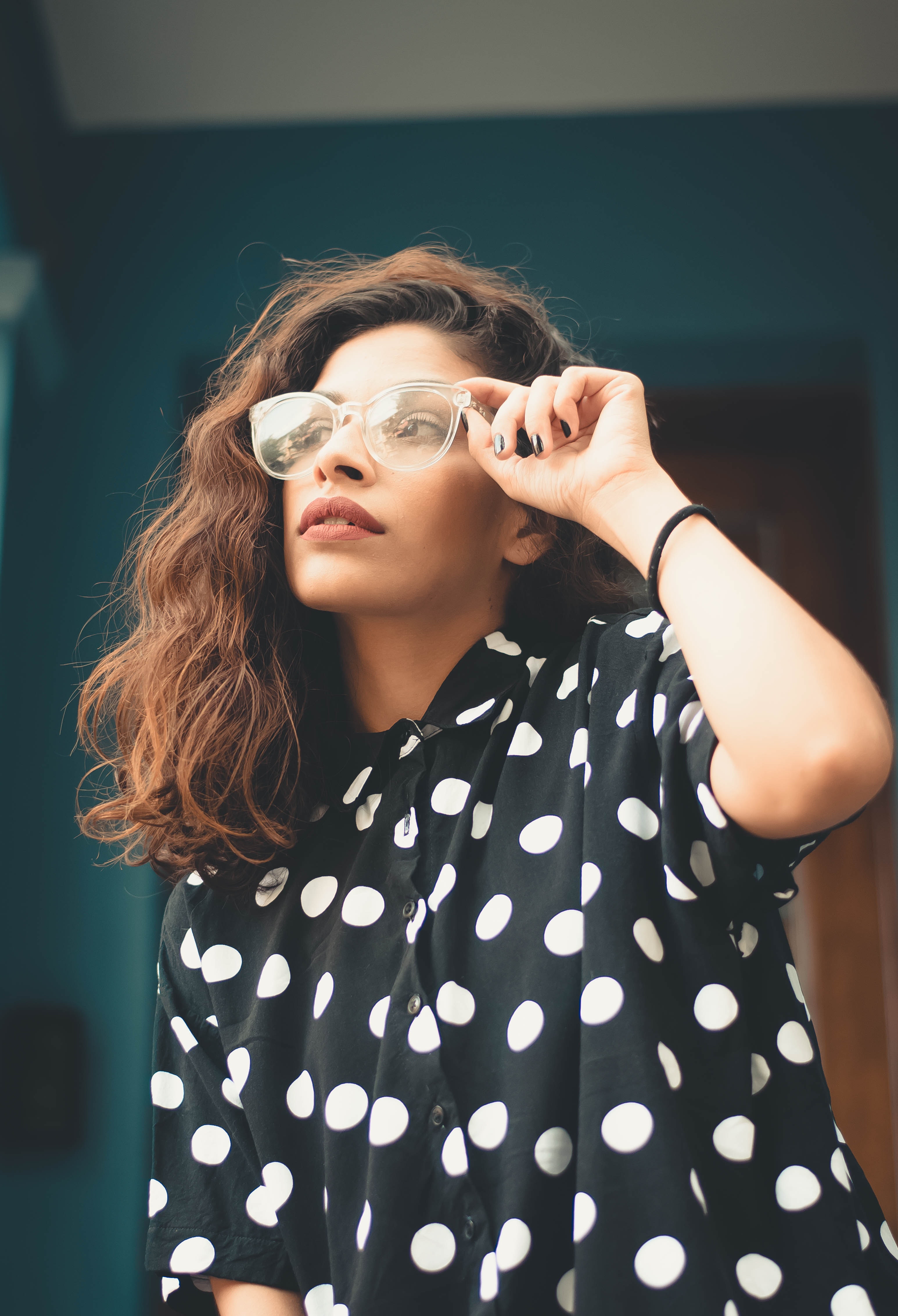 Woman wearing polka-dot shirt holding eyeglasses