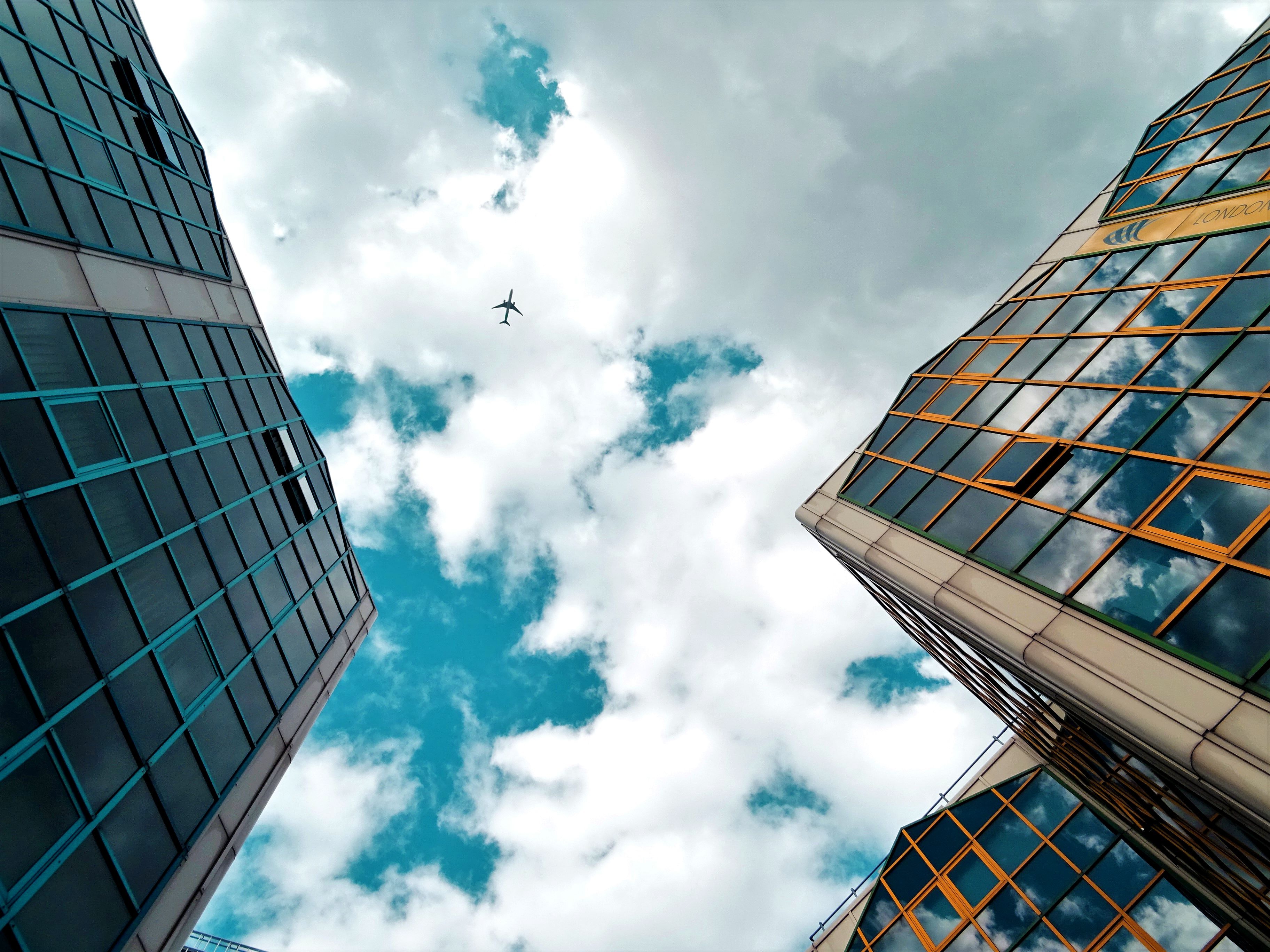 Worm's eye view of buildings and a plane flying between them