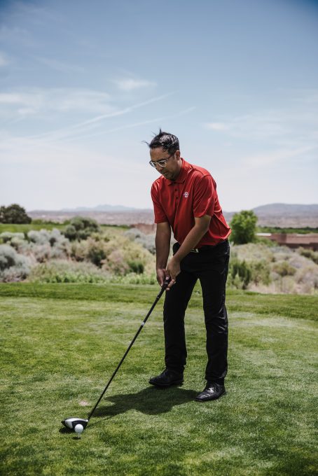 A man wearing a red t-shirt playing golf