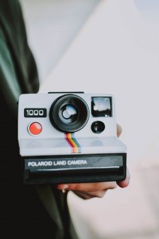 A person holding Polaroid Land Camera