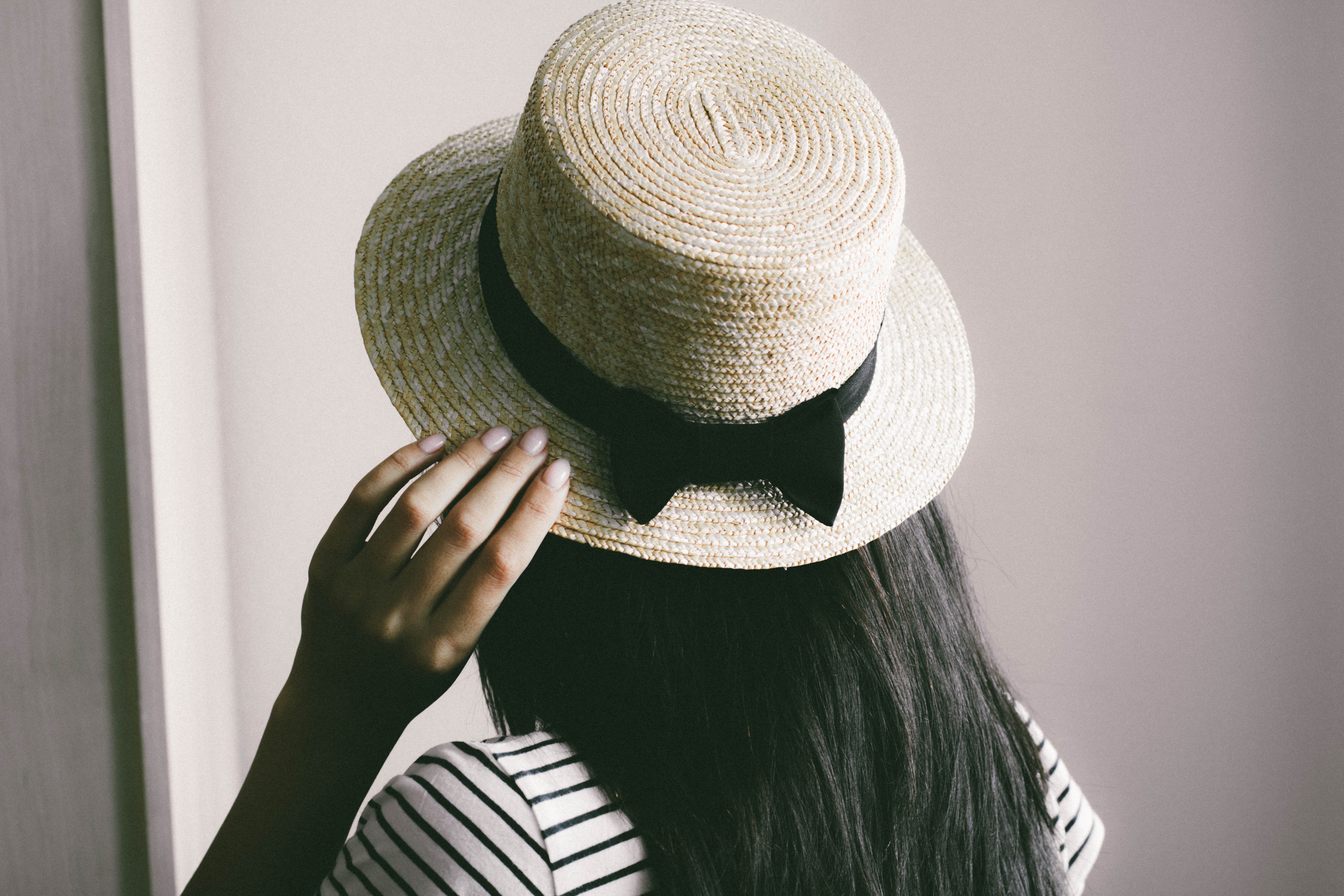 A woman holding a brown straw hat on her head