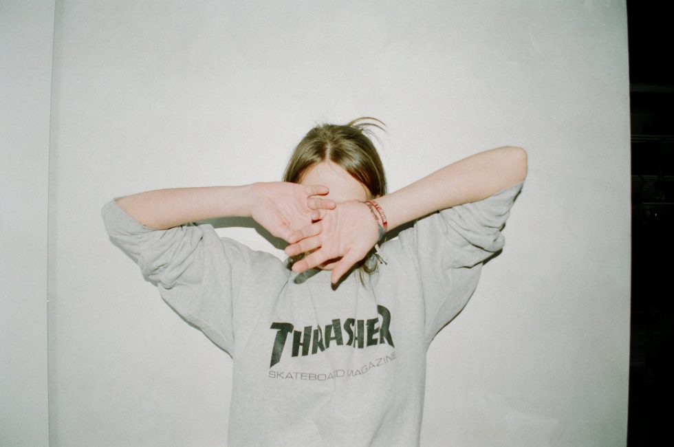 A woman in a gray sweatshirt covering her face with her hands
