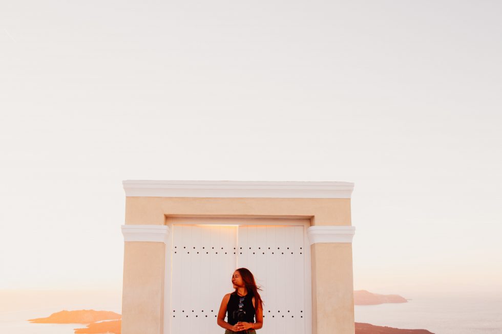 A woman in black sleeveless top posing in front of a white wooden door