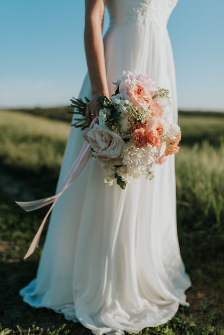 A woman wearing a white bridal gown while holding a bouquet flowers
