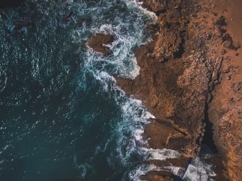 Aerial view of ocean waves and rocky coast