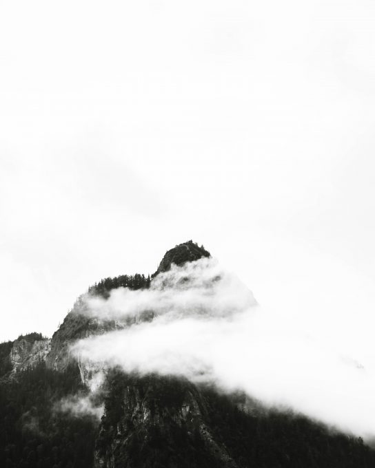 Monochrome photography of mountain under clouds