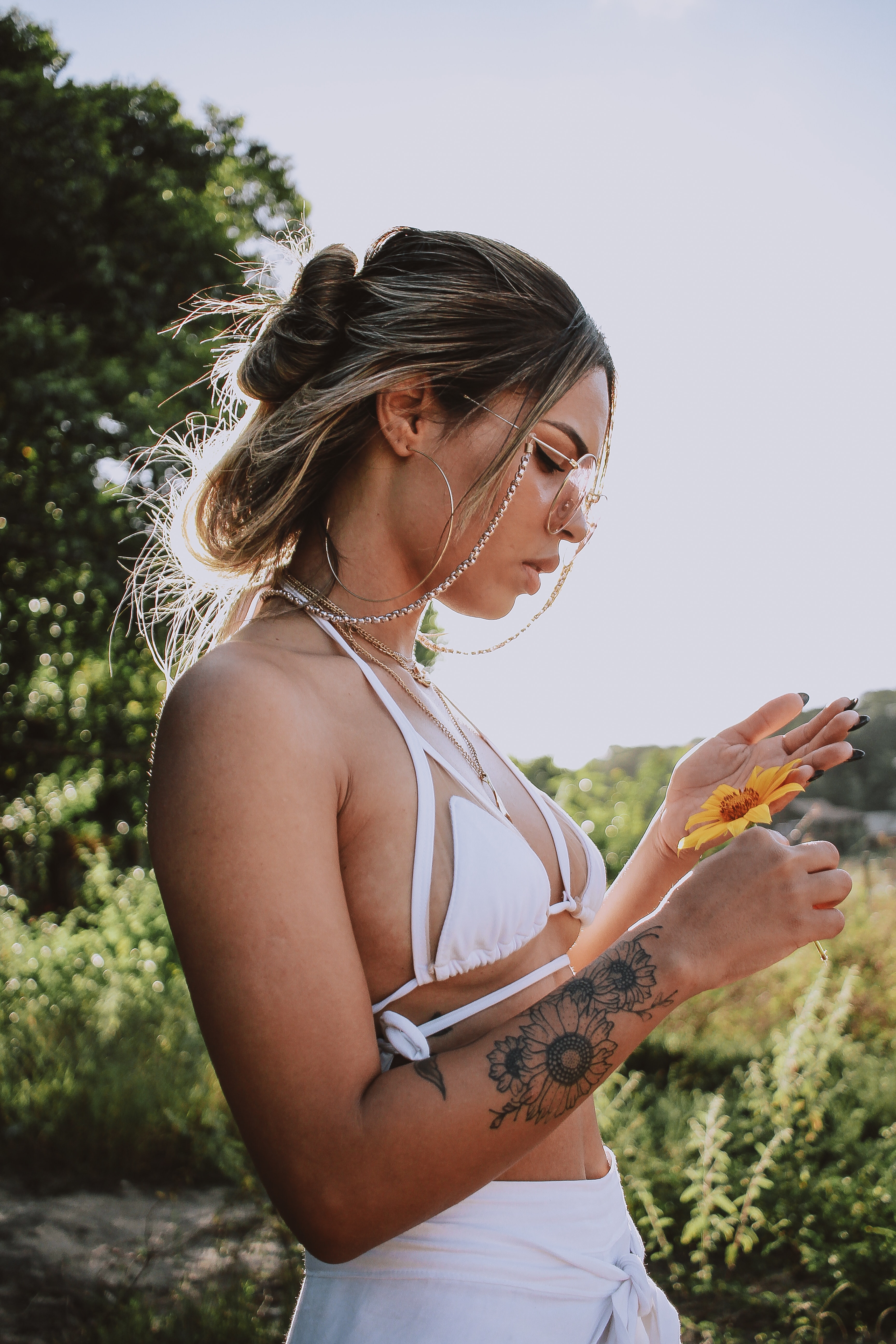 Photography of a woman with tattoos holding a yellow flower