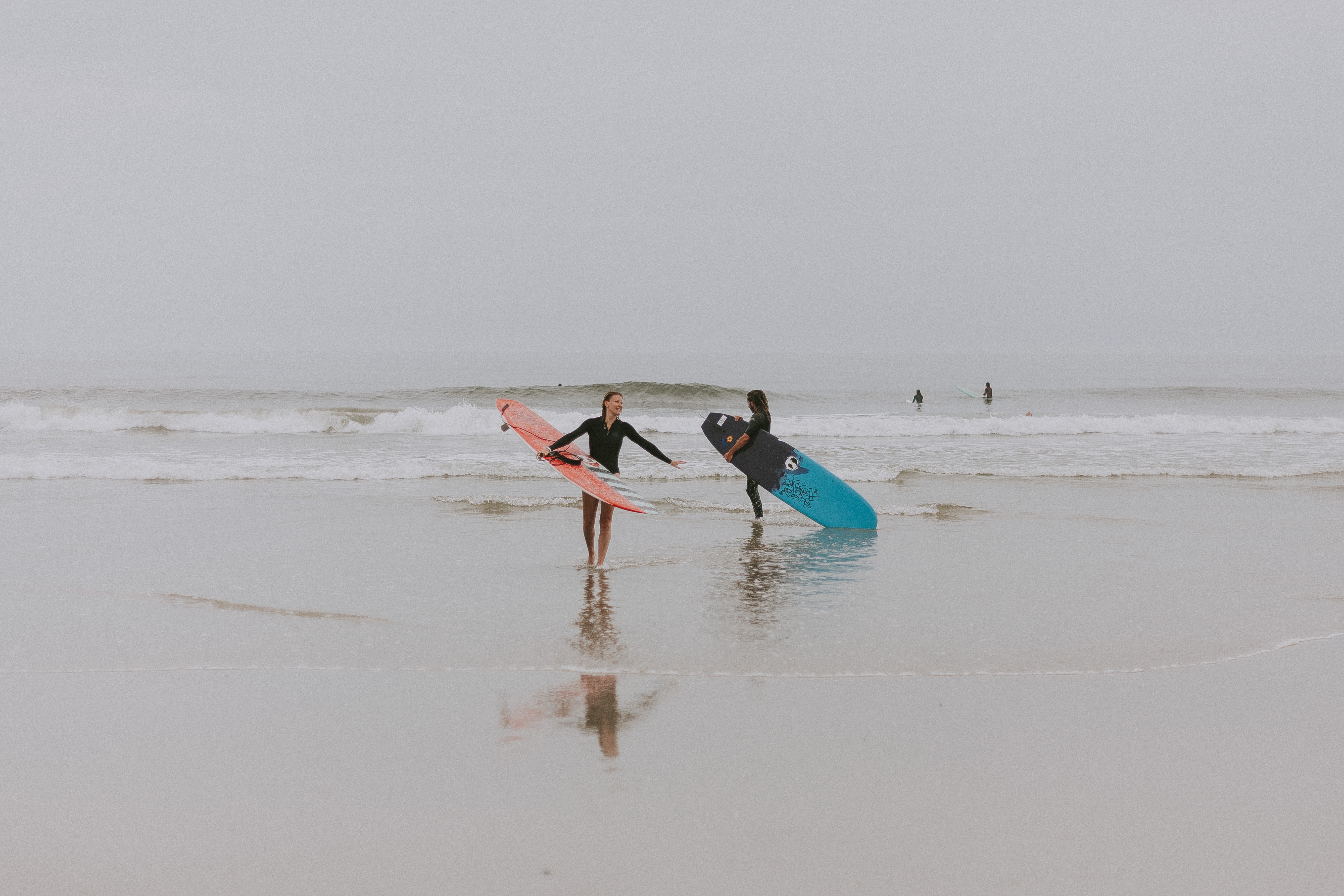 Photography of people on seashore holding surfboards during the fog