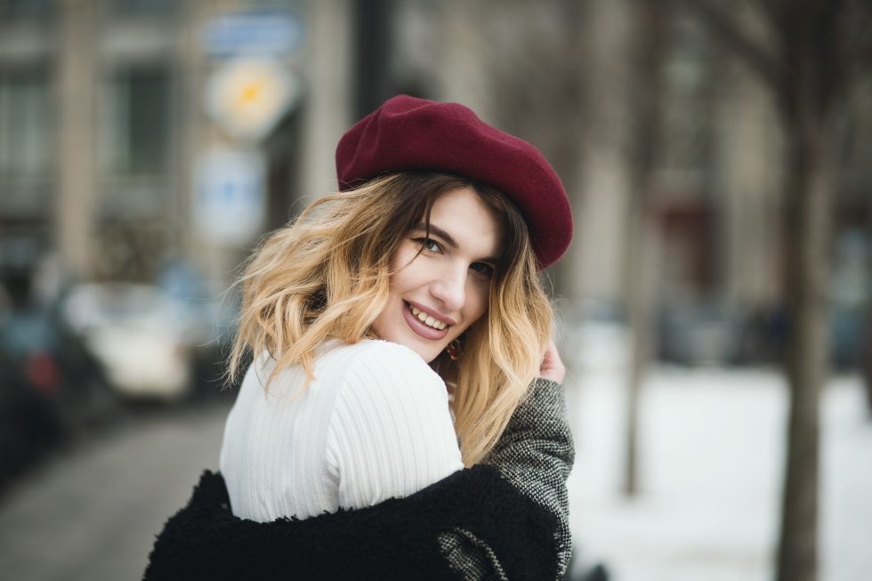 Selective focus photography of a smiling woman wearing a red hat