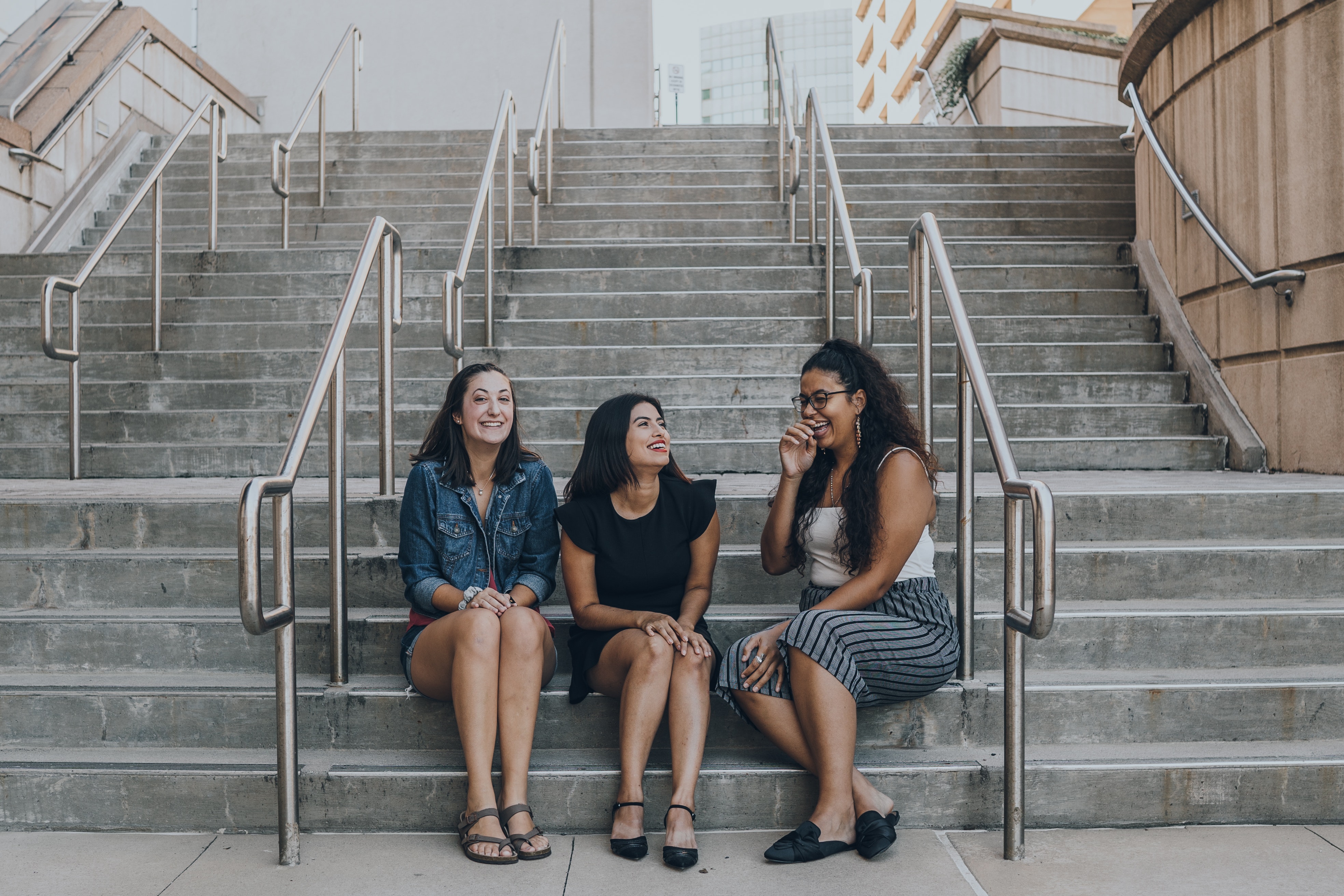 Three women smiling while sitting on stairs