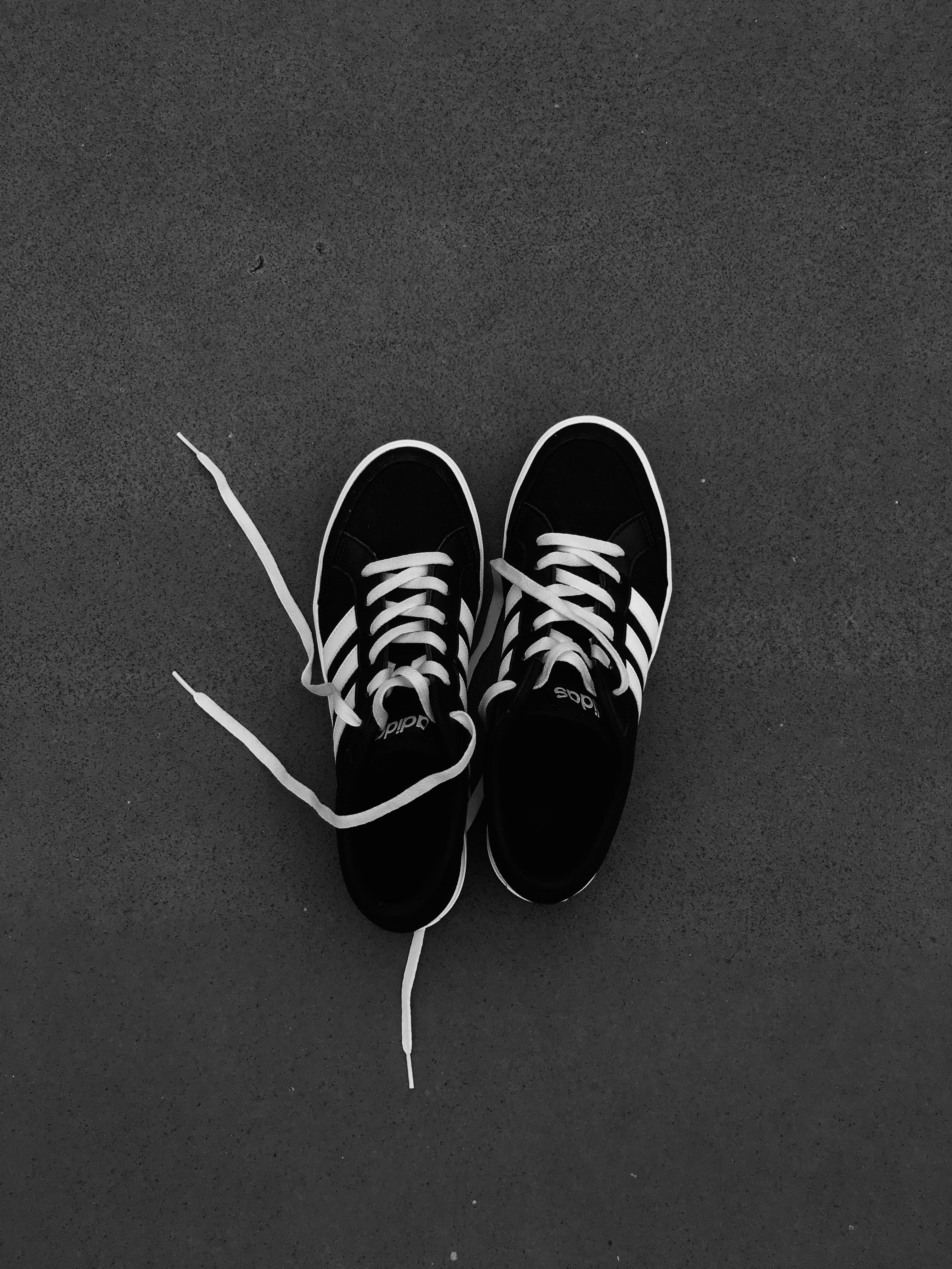 Top view of pair of black-and-white Adidas sneakers on the gray floor