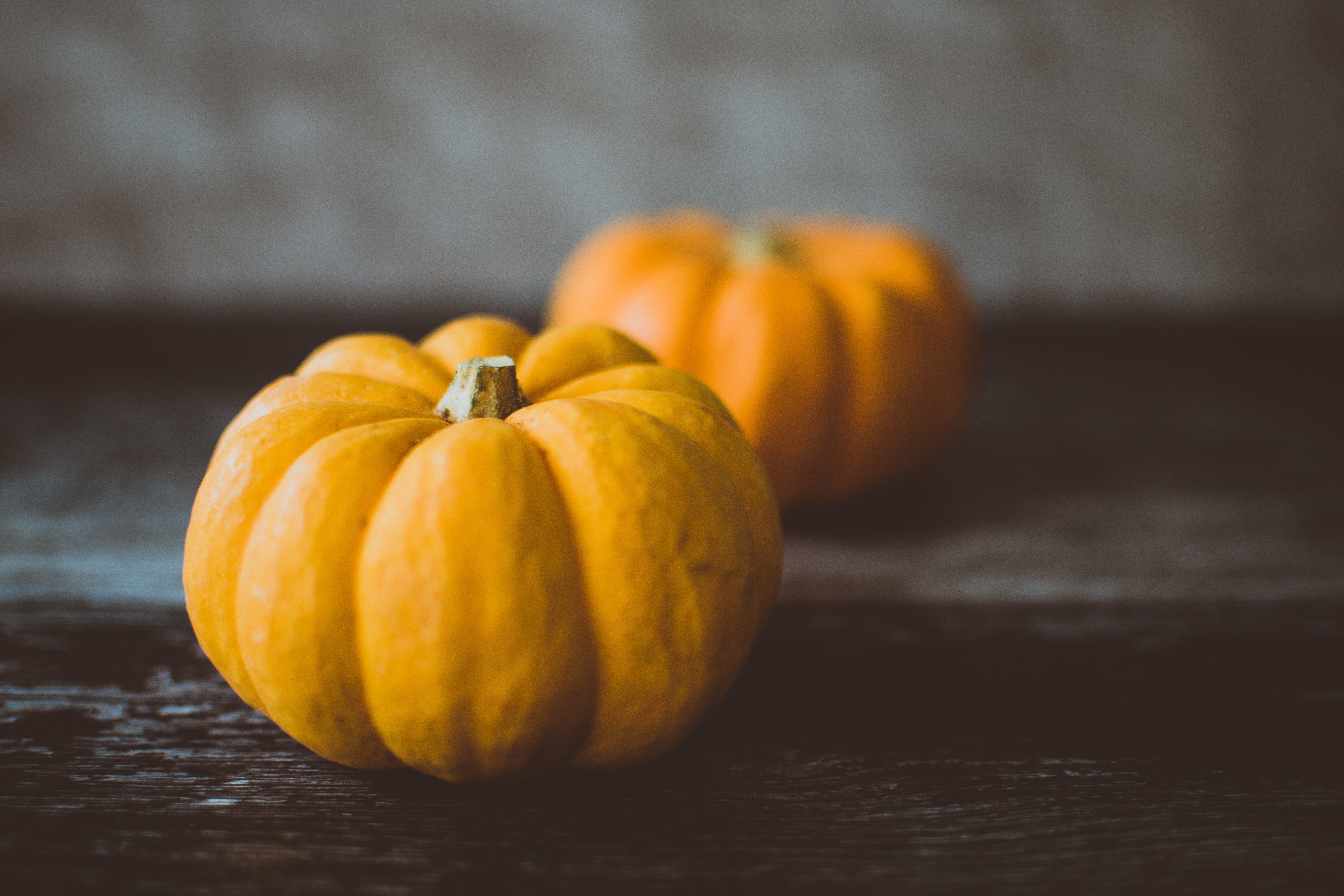 Two yellow pumpkins on a wooden table