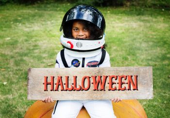 A girl in a spacesuit holding Halloween decor