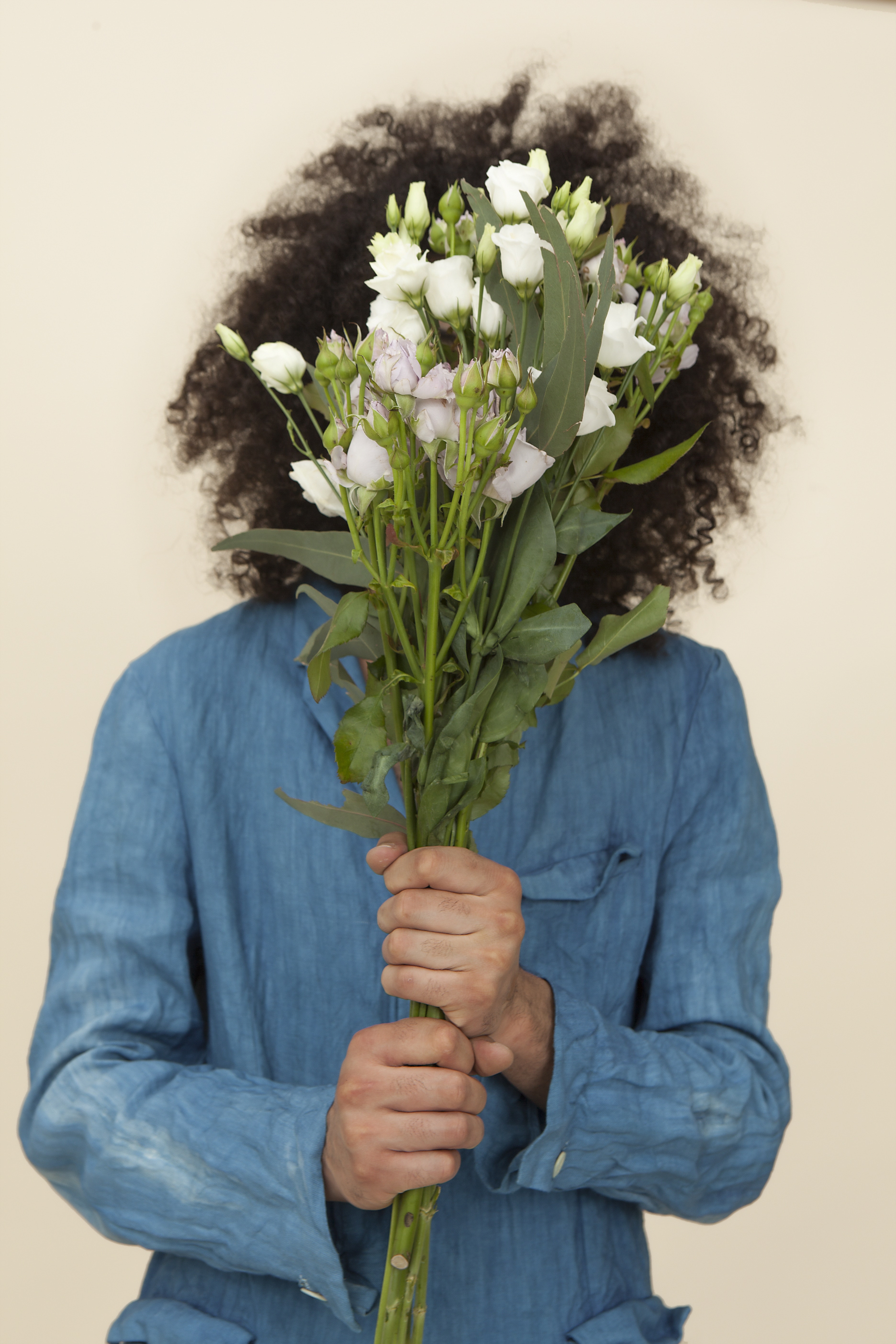 A person holding white a flower bouquet covering the face