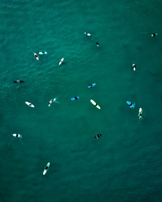 Aerial view of people using surfboards waiting for sea waves