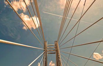 Low angle photo of a bridge under a blue sky and white clouds