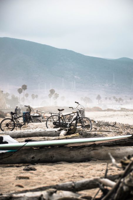 Two bicycles parked beside a log near shore
