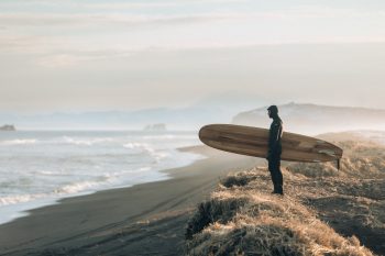 A man holding a surfboard and looking at the sea