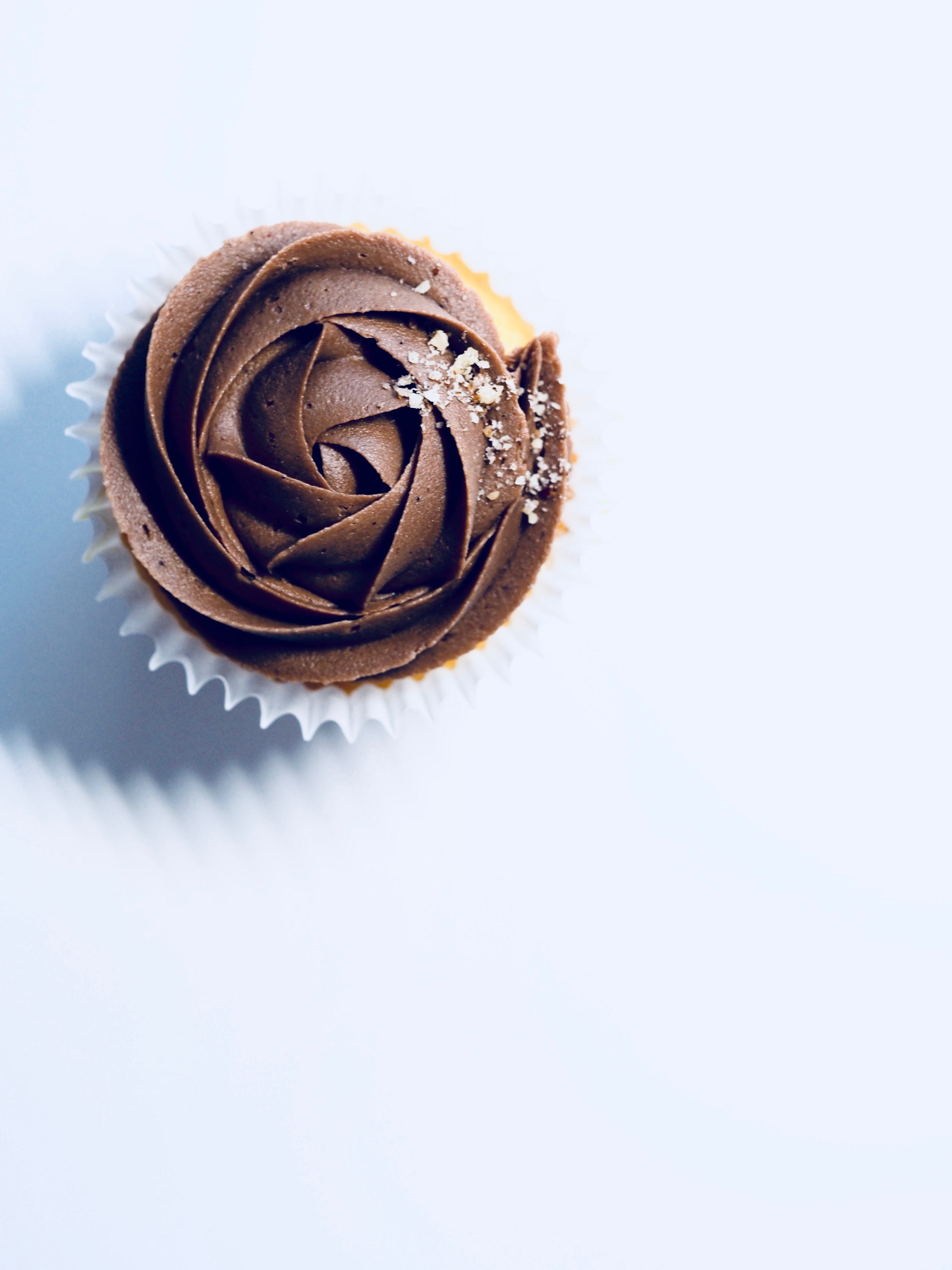 Flat view of a chocolate cupcake on a white surface