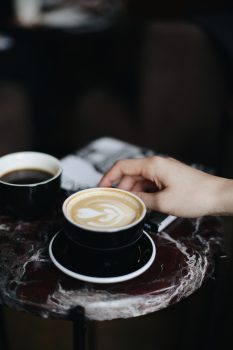 A person holding a cup of cappuccino