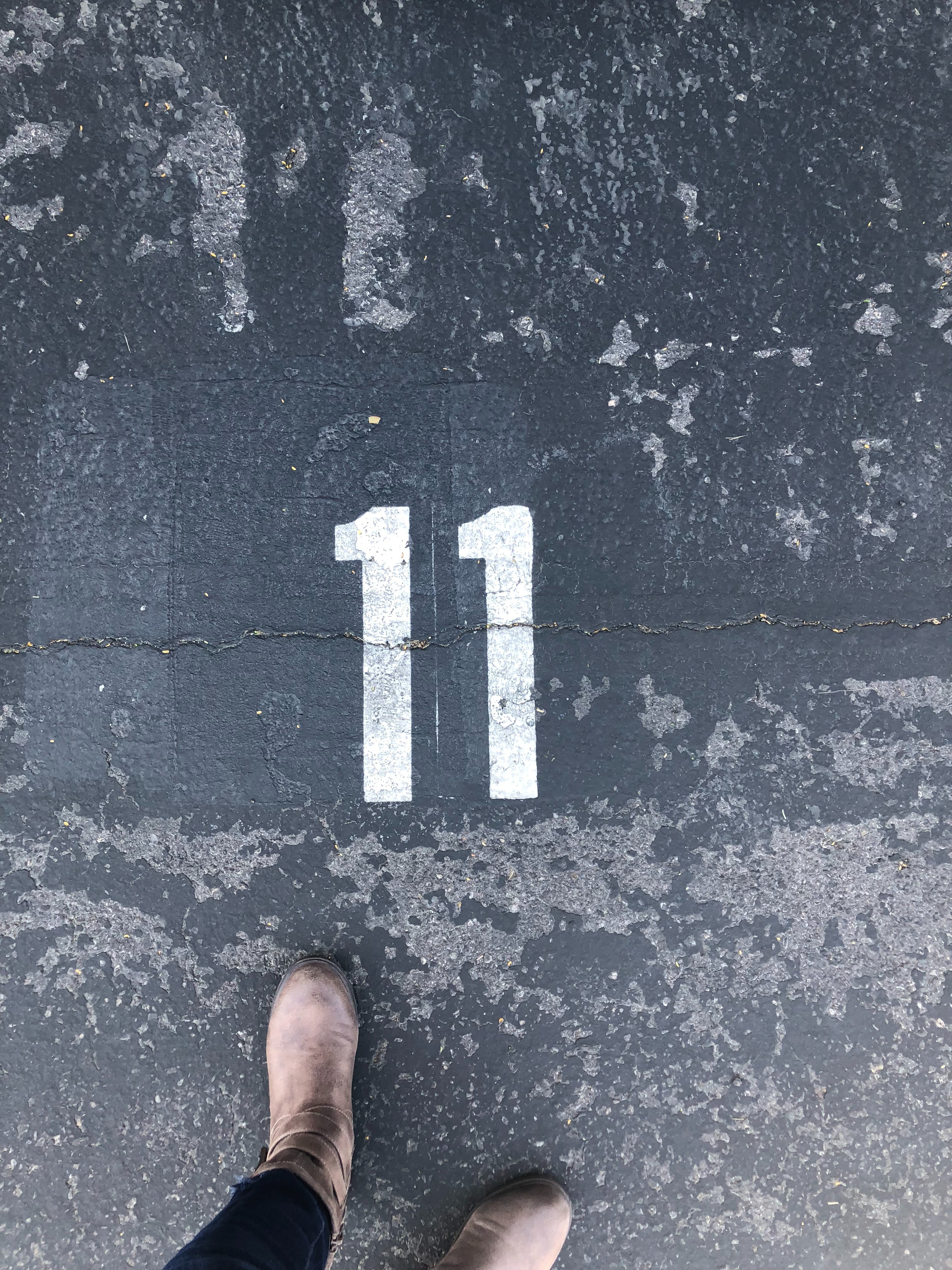 A person standing on the concrete floor with number 11 paint