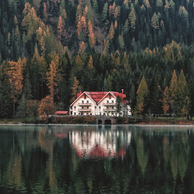 A white and orange house beside a forest and body of water
