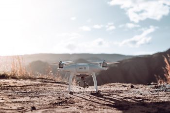 A white quadcopter drone on top of brown soil