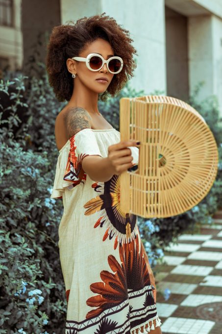 A woman in sunglasses wearing a white and brown floral dress