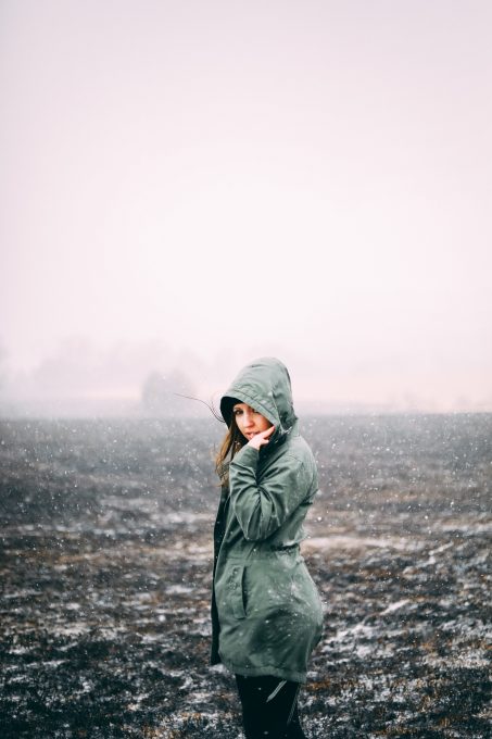 A woman standing on a grass field during snowfall