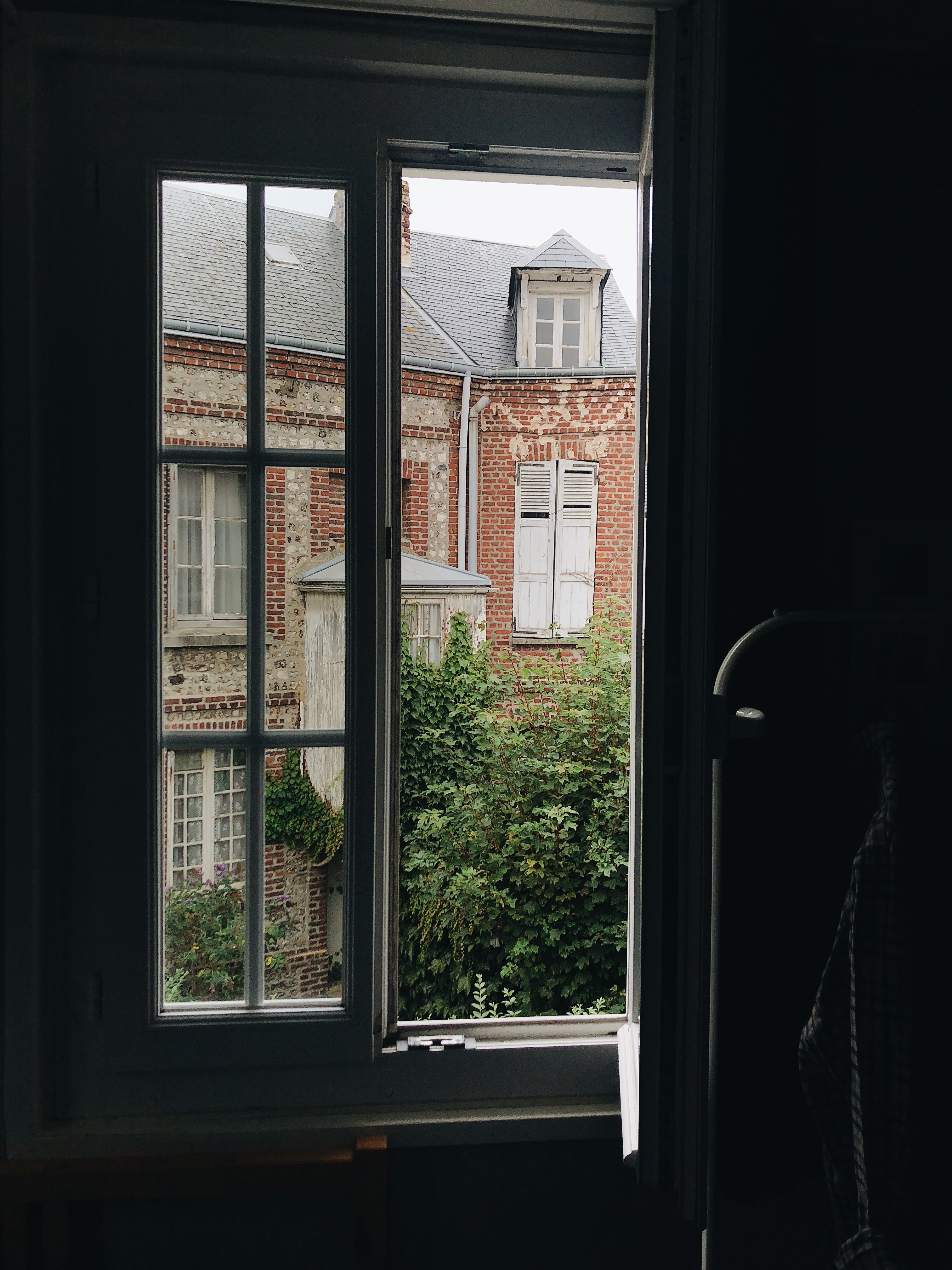An open window overlooking a red building