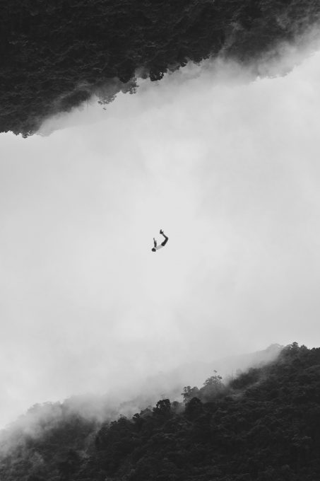 Black and white photo of a person falling in a foggy tropical forest