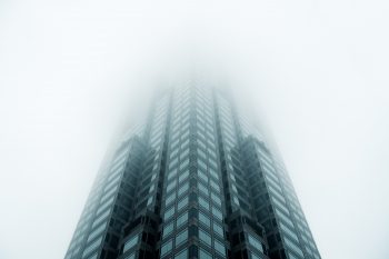 Low-angle photo of a high rise building standing in a fog