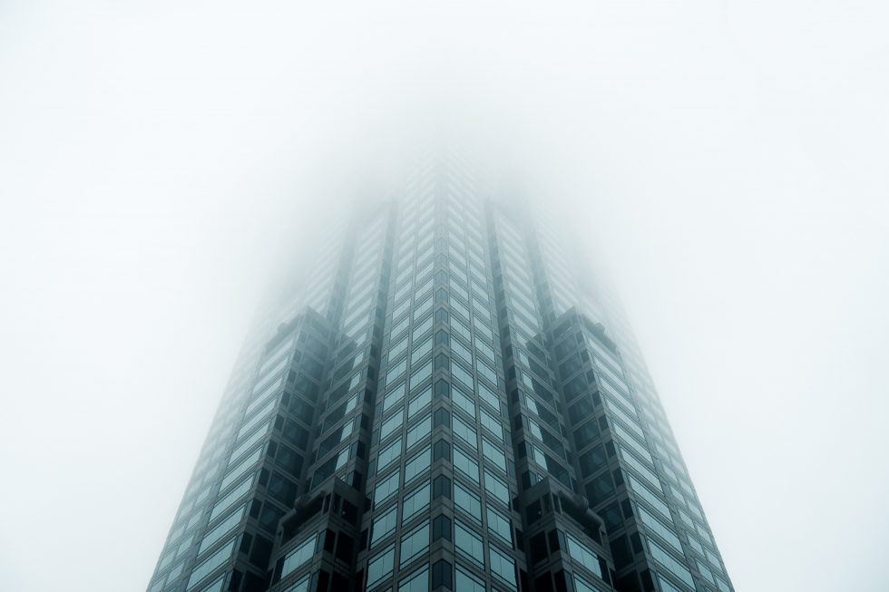 Low-angle photo of a high rise building standing in a fog