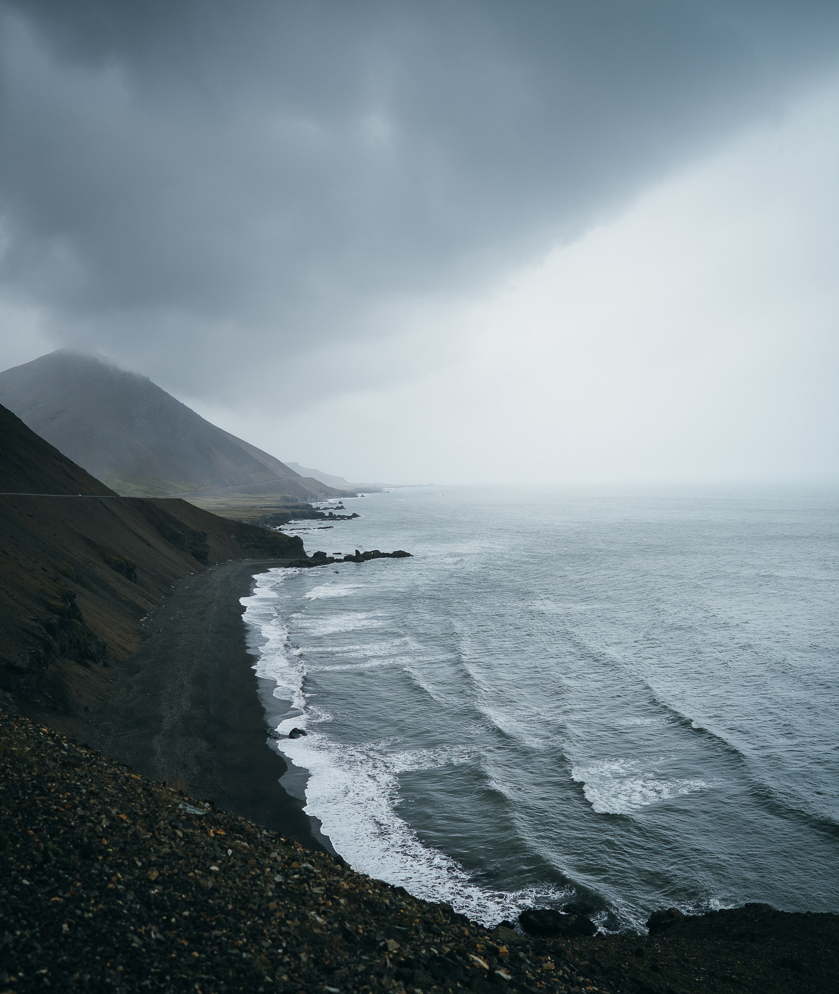 Photo of mountains by the ocean on a cloudy day