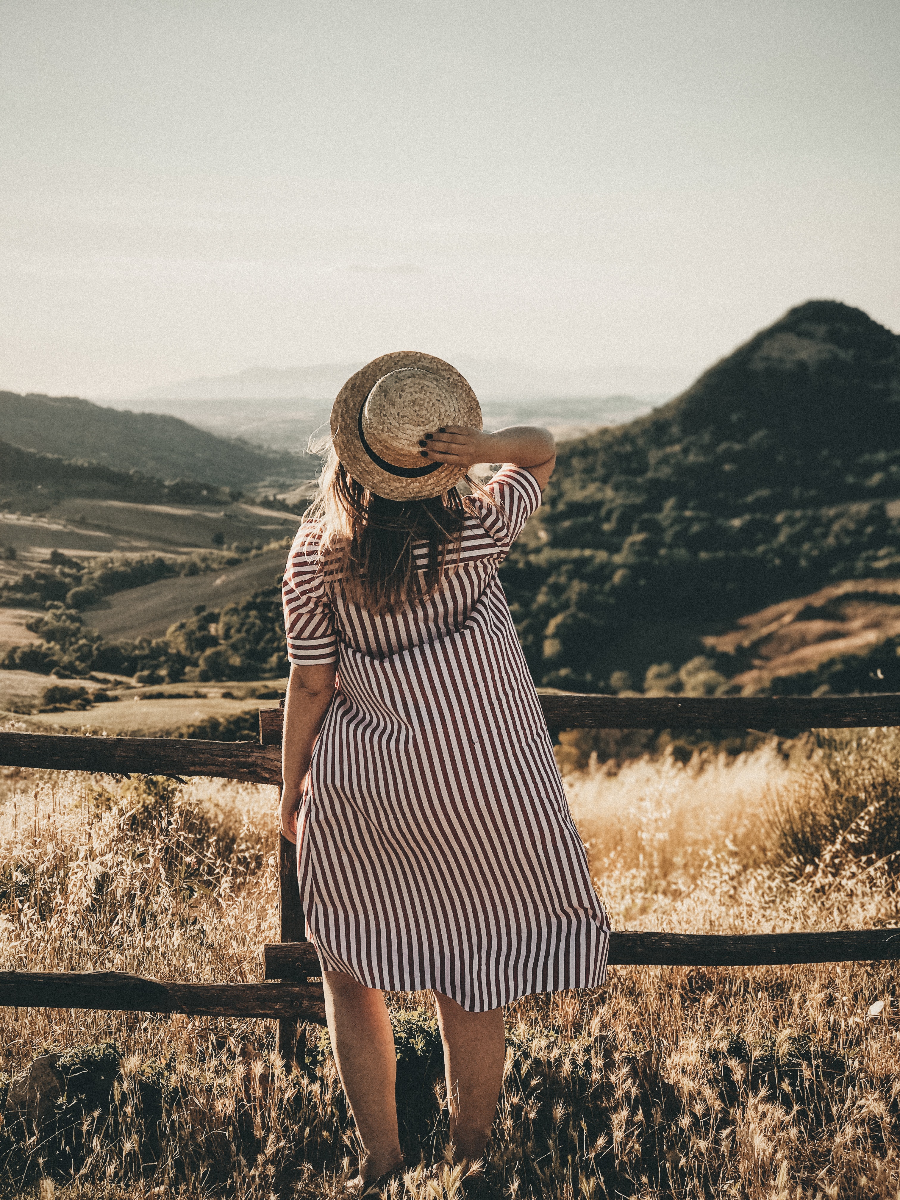 Selective focus photography of a woman holding a brown straw hat