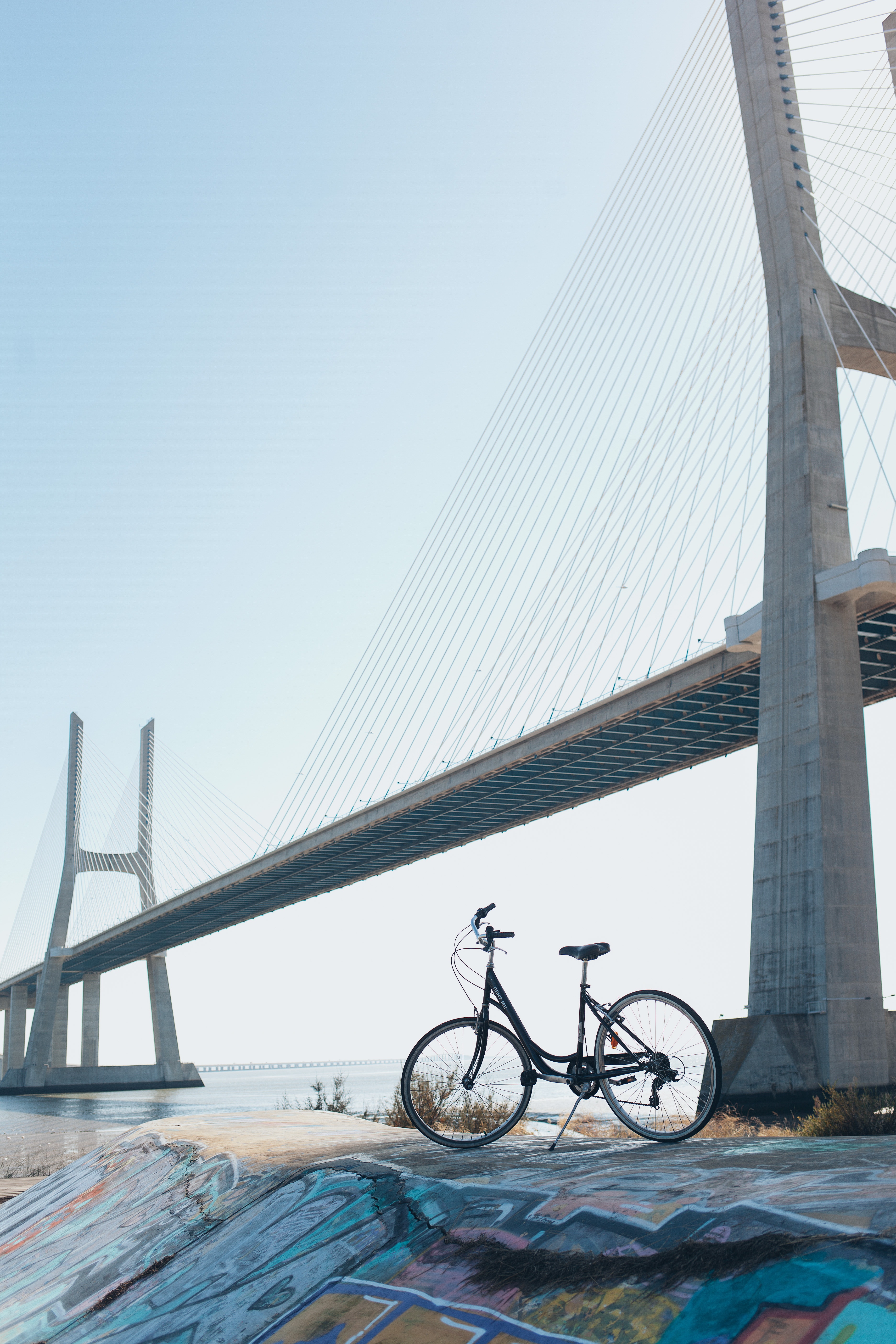 A bicycle parked under a gray concrete bridge