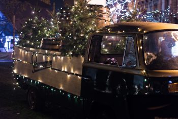 A classic brown single-cab truck with Christmas trees and string lights