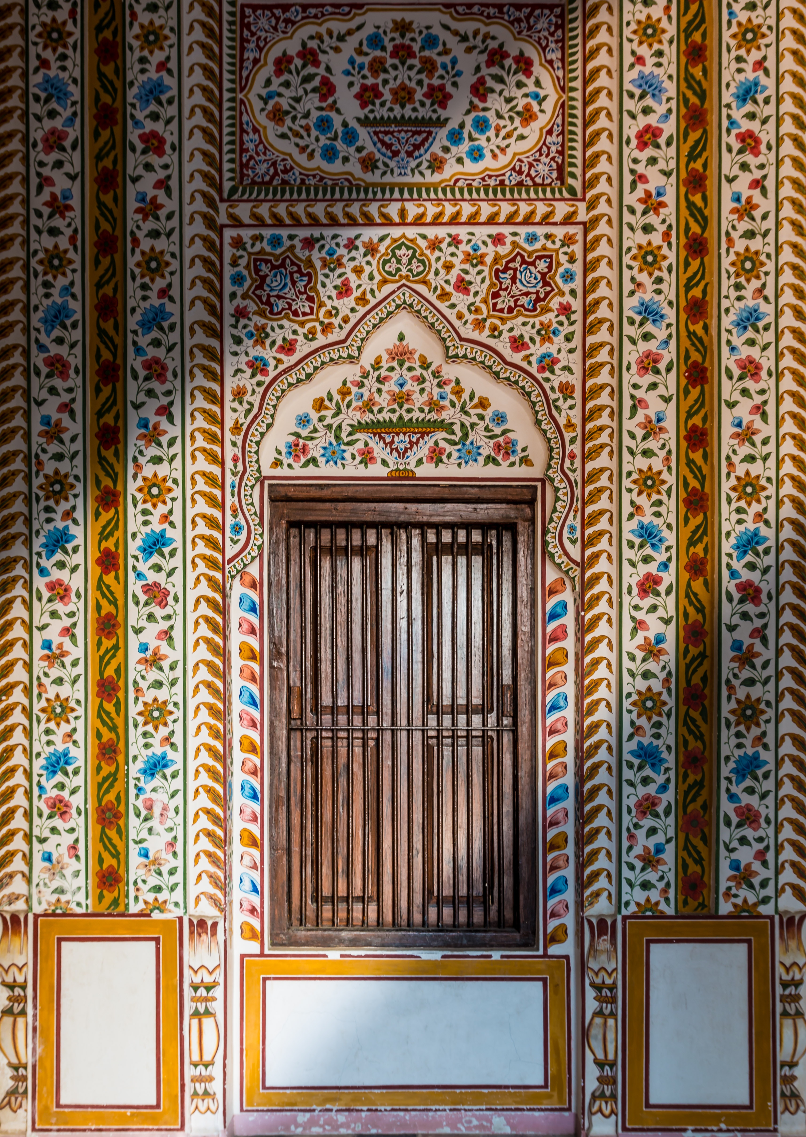 A closed brown wooden door surrounded by floral patterns