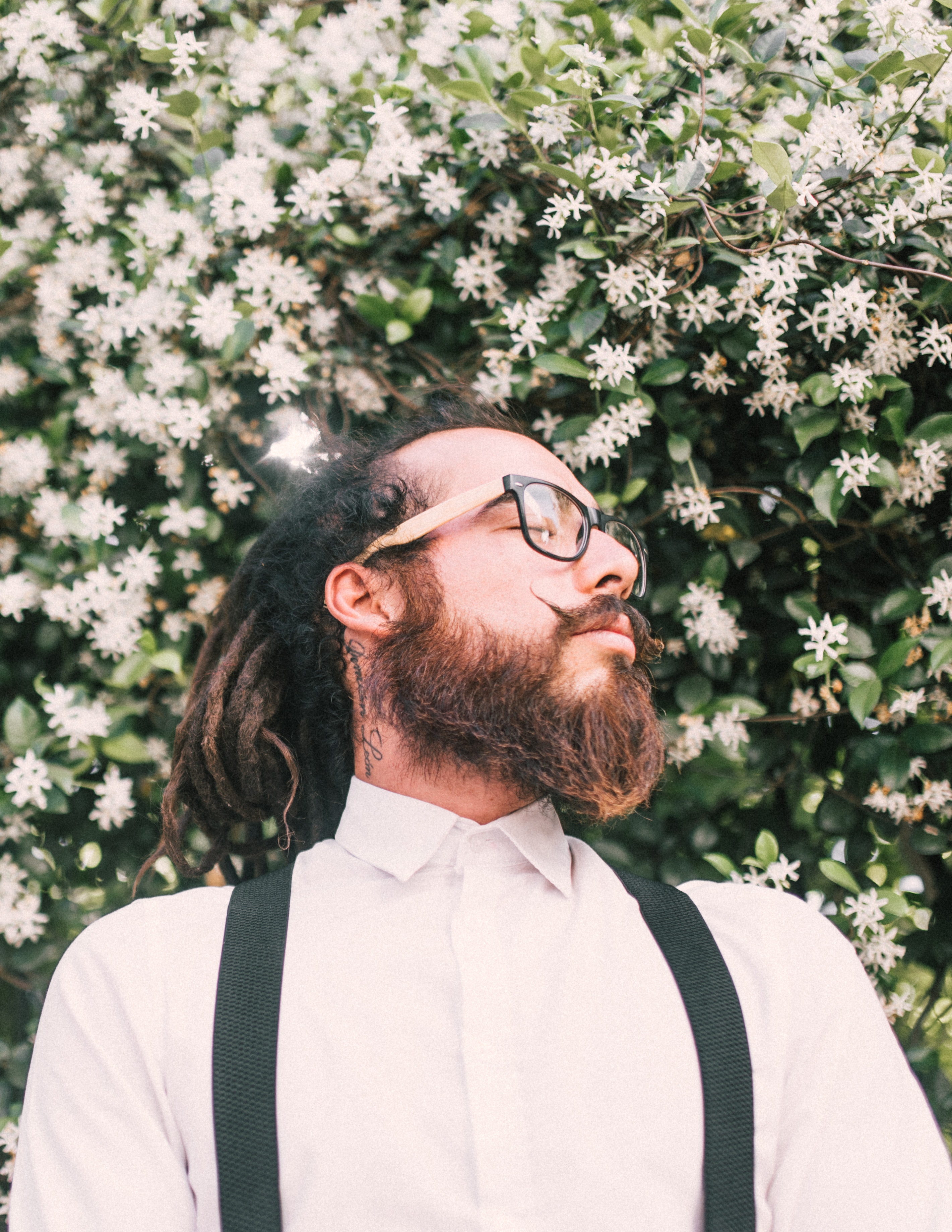 A man with dreadlocks and a beard wearing a white shirt and eyeglasses